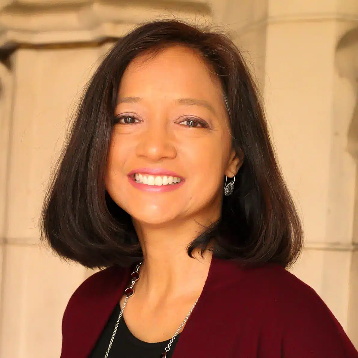 A smiling woman wearing a burgundy jacket.